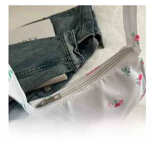 Close-up of white mini floral bag showing pink ribbon prints and smooth zipper closure