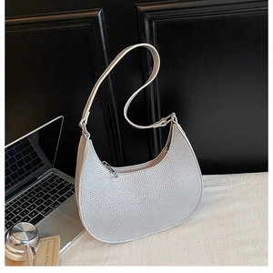 Macro detail of silver pebbled leather texture on a minimalist crescent hobo shoulder bag