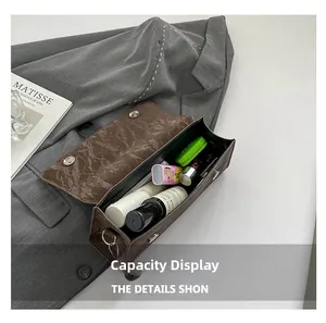 Capacity display of brown pleated leather baguette bag with cosmetic items inside