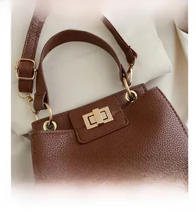 Detail of dark brown pebble leather bag with gold hardware ring and metallic turn-lock