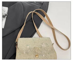 Detail showing the floral embroidery and gold twist-lock on a beige woven saddle bag