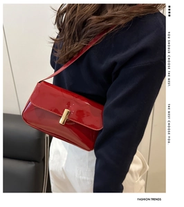 Detail of red patent leather shoulder bag with a polished golden rectangular metal buckle