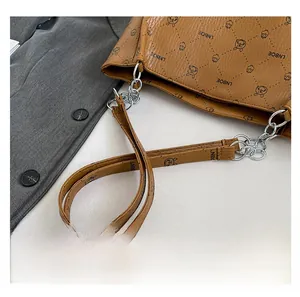 Detail view of brown tote bag featuring cartoon prints and silver metal chain strap