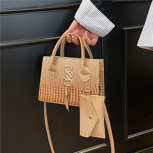 Bolso de mano color champán con grabado de cocodrilo, logotipo metálico y borla elegante