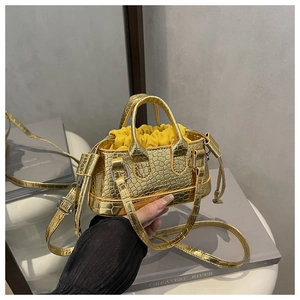Close-up of golden faux crocodile skin texture and drawstring interior on a handbag