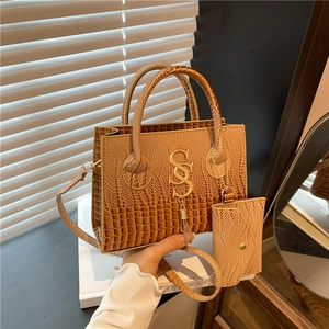 Bolso bandolera marrón con diseño de cocodrilo, logo dorado y borla decorativa