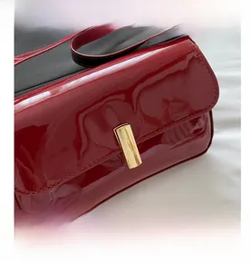 Detail of red patent leather handbag with gold clasp and sleek high-gloss finish