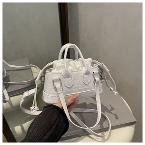 Detail of white crocodile embossed mini handbag with drawstring liner and shoulder strap