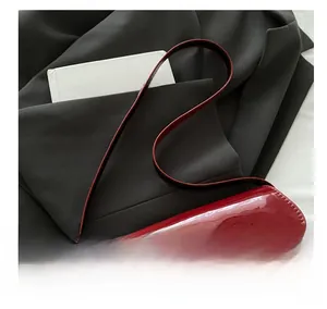 Detail of red patent leather shoulder bag with a sleek gold metal buckle closure