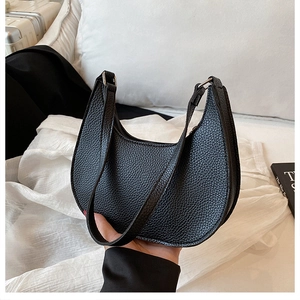 Detail of black lychee grain leather crescent bag with silver metallic buckle
