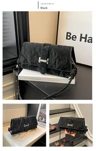 Close-up of black ruched leather baguette bag with silver buckle and knot detail