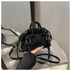 Detail of mini black crossbody bag featuring crocodile texture and drawstring closure
