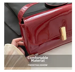 Close-up of red patent leather shoulder bag featuring a gold rectangular metal clasp