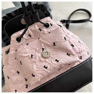 Détail du tissu matelassé rose et du similicuir noir sur un sac à dos à cordon de serrage