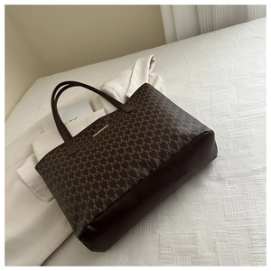 Macro view of large tote bag with brown monogram print and premium leather details