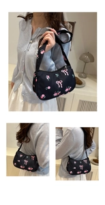 Detail of black nylon shoulder bag featuring pink bow and floral prints in lifestyle setting