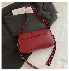 Détail du sac rouge mat avec œillets métalliques argentés sur une veste grise