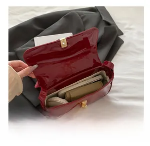 Internal view of red patent leather crossbody bag showing capacity for phone and cosmetics