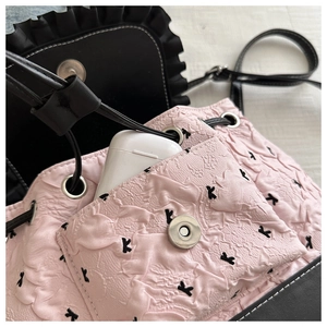 Détail du tissu plissé rose avec broderie K noire et fermoir magnétique argenté