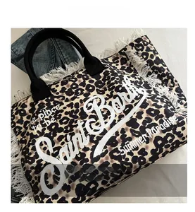 Detail shot of leopard print tote bag featuring white fringe edges and circular handles