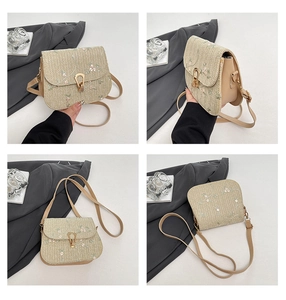 Detail showing floral embroidery and golden horseshoe buckle on a straw crossbody bag