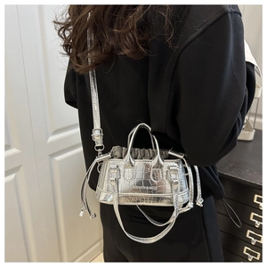 Detail of silver crocodile pattern mini tote with drawstring closure and shoulder strap