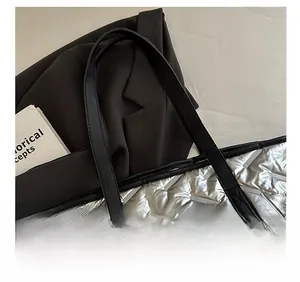 Detail of silver metallic quilted tote bag featuring wide black leather shoulder straps