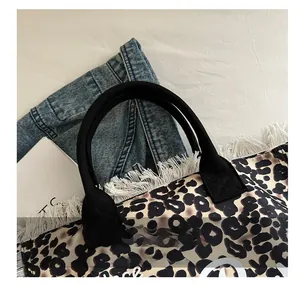 Close-up of leopard print canvas tote bag featuring black handles and white fringe details
