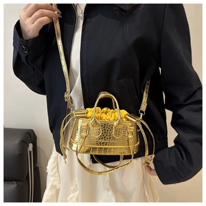 Detail of mini gold crocodile textured crossbody bag with yellow drawstring liner and strap