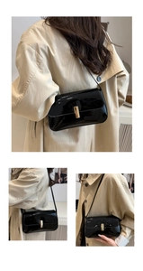 Detail of black patent leather small square bag with vertical gold metal clasp