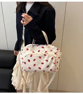 Detail of strawberry print on cream corduroy crossbody bag with adjustable strap