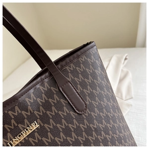 Close-up of brown leather tote bag with M-pattern print and gold metallic logo detail