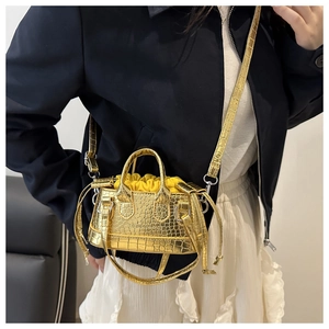 Detail of golden crocodile texture mini bag with drawstring and brand logo