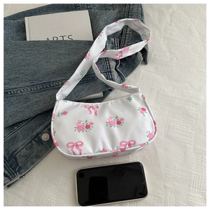 Detail of floral underarm bag with pink roses, bow patterns, and phone size reference