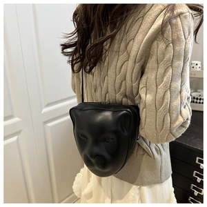 Detail view of a modern black matte shoulder bag with a unique 3D animal face sculpture