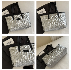 Detail view of silver quilted tote bag with black handles and metallic finish texture