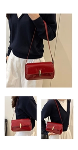 Detail of red patent leather shoulder bag with gold clasp and sleek rectangular flap