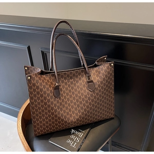 Detail of classic brown monogram tote bag with double handles and gold hardware