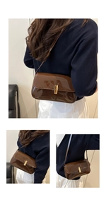 Detail of glossy brown patent leather shoulder bag with rectangular gold metal clasp