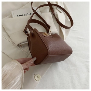 Detail of dark brown lychee leather bag featuring a gold-tone twist lock closure