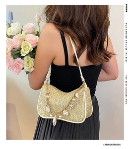 Détail du sac sous le bras en paille tissée avec coquillages, perles et chaîne dorée