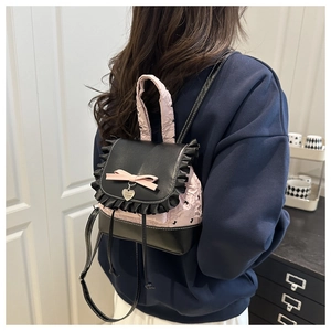 Détail de bordure en dentelle et breloque cœur sur mini sac à dos contrasté noir et rose