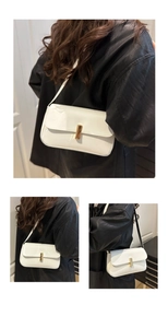 Macro detail of white patent leather shoulder bag featuring a sleek gold cylindrical clasp