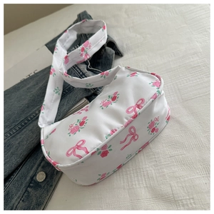 Detailed close-up of white shoulder bag featuring pink rose and ribbon floral patterns