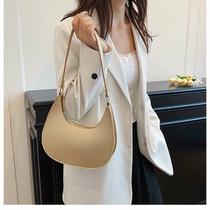 Close-up of champagne gold crescent bag showing luxury lychee leather texture and metal zipper