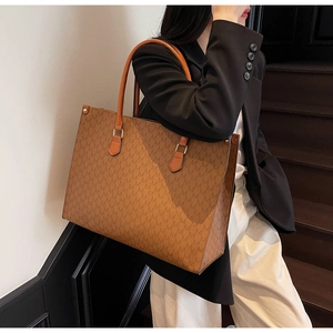 Detail of caramel tote bag featuring textured M-letter monogram print and sturdy handles