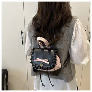 Detail of mini backpack featuring black faux leather, pink quilting, and silk bow accent