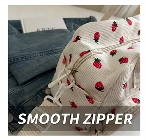 Detail of strawberry print corduroy bag showing smooth zipper and fabric strap