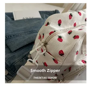 Detail of strawberry print corduroy bag showing smooth zipper and fabric strap