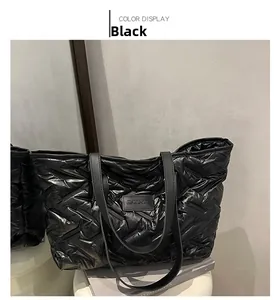 Detail of black quilted tote bag with glossy finish and brand label on front surface